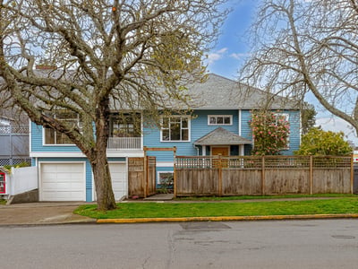 Spacious blue home with a fenced yard, featuring unique architecture and convenient garage access.