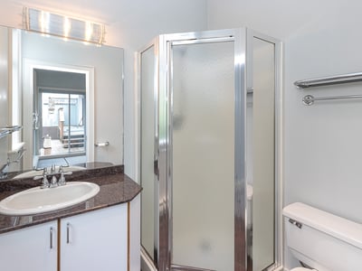 Modern bathroom featuring a glass shower, sleek countertops, and ample storage for convenience and functionality.