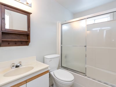 This well-equipped bathroom features a sleek shower enclosure and convenient storage space, perfect for everyday use.