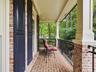 Inviting porch space with brick flooring and views of lush greenery, perfect for outdoor relaxation.