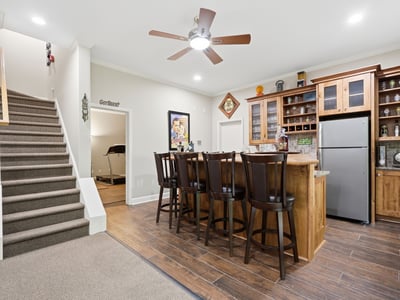 Spacious entertainment area featuring a modern kitchen bar with ample seating and convenient staircase access.