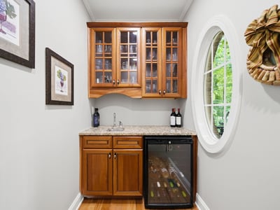 Perfect for entertaining, this cozy wine nook features stylish cabinetry and a compact fridge for easy access.