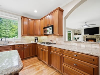 Bright kitchen featuring rich wood cabinetry, spacious countertops, and views of the landscaped outdoor area.