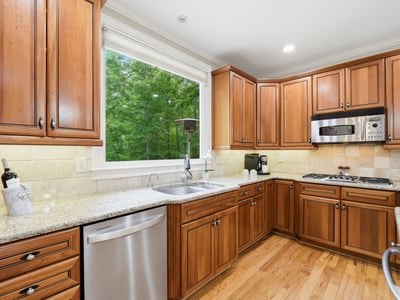 Bright kitchen featuring custom wood cabinetry, modern appliances, and ample counter space overlooking a lush outdoor view.