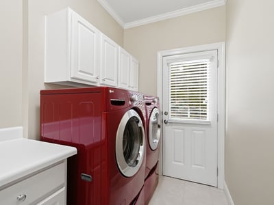 Bright and functional laundry room featuring modern red appliances and ample storage space.