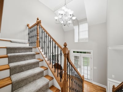 Bright and inviting entryway features a spacious staircase with elegant railings and abundant natural light.