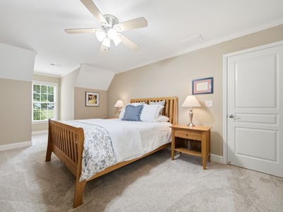 Bright and inviting bedroom featuring plush carpeting, modern ceiling fan, and ample natural light.