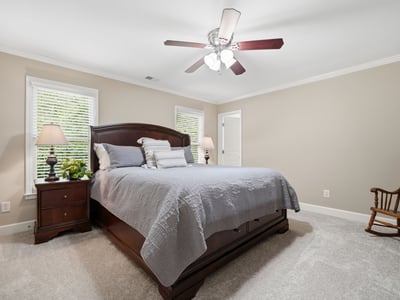 Spacious bedroom featuring natural light, a ceiling fan, and ample room for relaxation and comfort.