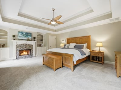 This spacious master bedroom features vaulted ceilings, a cozy fireplace, and ample built-in storage solutions.