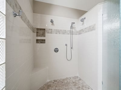 Spacious, modern shower with multiple showerheads and built-in shelving, ideal for a refreshing experience.