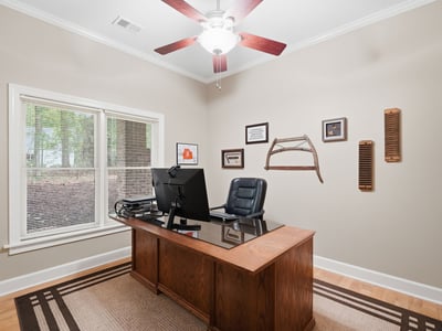 Bright home office featuring a spacious desk, ample natural light, and a tasteful decor theme.