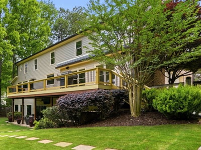 Discover a spacious home with a large deck, surrounded by lush landscaping and vibrant greenery.