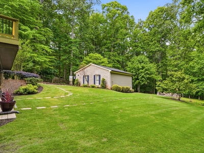 Nestled among lush trees, this property features expansive green space and a versatile outbuilding.