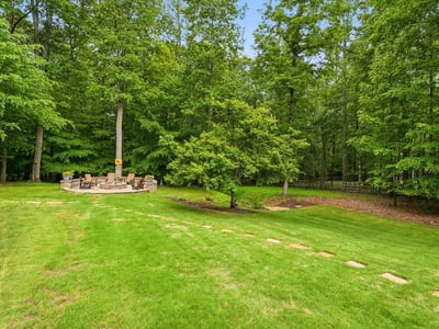 Spacious backyard with a cozy fire pit surrounded by lush greenery, perfect for gatherings and relaxation.