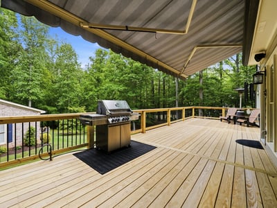 Expansive deck with built-in grill, surrounded by lush greenery, perfect for outdoor gatherings and relaxation.