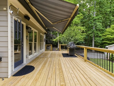 Spacious deck with awning, perfect for outdoor gatherings and overlooking lush green surroundings.