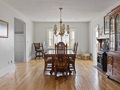 Spacious dining area features ample natural light, classic furnishings, and a cozy fireplace for gatherings.