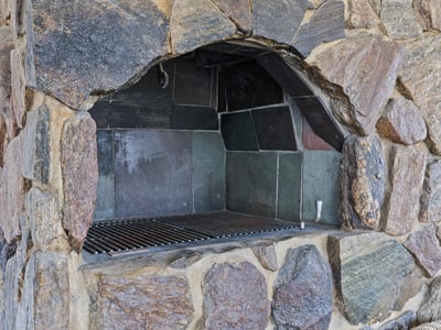 Discover a unique outdoor space featuring a robust stone fireplace, perfect for gatherings and cooking.