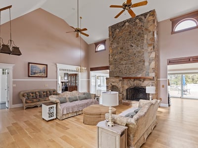Spacious living area features a stunning stone fireplace and large windows, perfect for natural light.