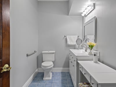 Bright and functional bathroom featuring modern fixtures, ample storage, and sleek blue tile flooring.