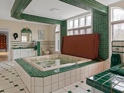 Spacious bathroom featuring unique tile work, a large jetted tub, and abundant natural light.