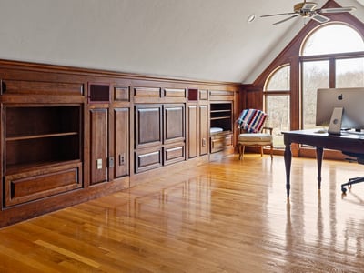 Bright, spacious office featuring wooden paneling, ample storage, and large windows for natural light.