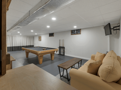 Spacious recreation room featuring a pool table, cozy seating, and ample lighting for entertaining.