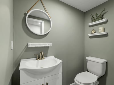 Modern bathroom featuring a sleek vanity, round mirror, and practical shelving for added storage.