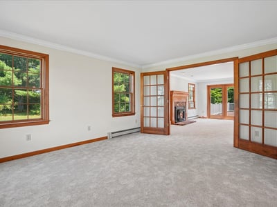 Spacious living area with abundant natural light, featuring French doors and a cozy fireplace for gatherings.