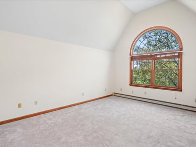 Bright, spacious room featuring a large arched window that offers abundant natural light and scenic views.