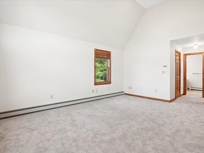 Spacious room with vaulted ceiling, large windows, and neutral carpeting, ready for your personal touch.