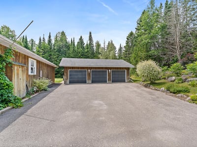 Spacious property featuring ample parking and garage space, surrounded by lush greenery and natural beauty.