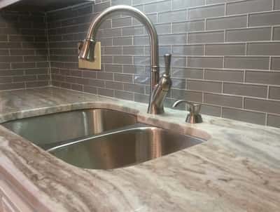 Modern kitchen featuring a sleek granite countertop and a contemporary stainless steel sink setup.