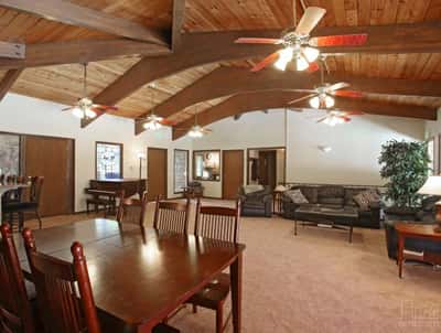Spacious living area features exposed wood beams, ceiling fans, and ample natural light for comfortable gatherings.