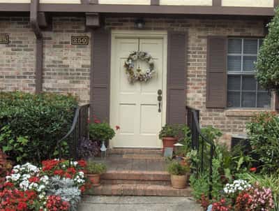 This inviting front entry features vibrant landscaping and a decorative wreath, enhancing its warm appeal.