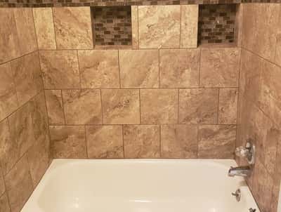 Modern bathroom featuring a textured tile design, built-in niches, and a sleek bathtub for comfort.