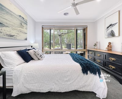 Spacious bedroom featuring large windows, natural light, and a view of lush outdoor greenery.