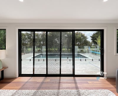Bright and inviting living space with expansive glass doors opening to a private pool and outdoor deck.