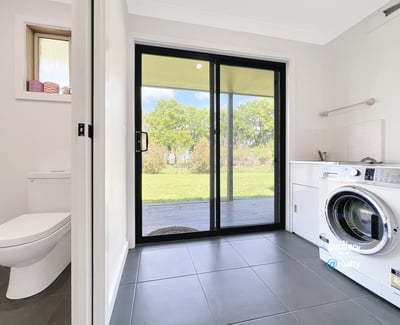 Bright laundry room featuring a washing machine, ample storage, and direct access to the outdoor space.