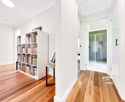Bright and inviting interior featuring wooden floors, a spacious hallway, and a versatile bookshelf area.