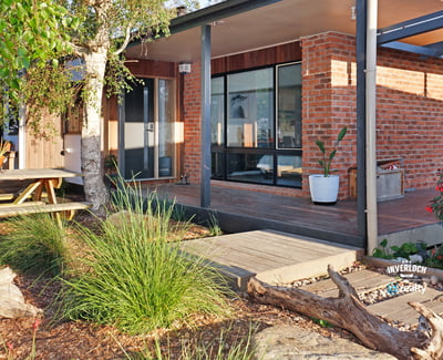 Contemporary home featuring expansive windows and an inviting outdoor space surrounded by lush greenery.
