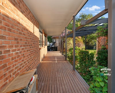 Inviting walkway lined with brick and greenery, leading to a secluded outdoor living space.