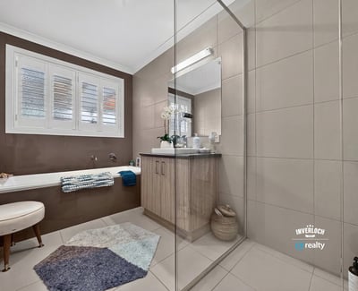 Modern bathroom featuring a spacious walk-in shower, double vanity, and natural light from large windows.