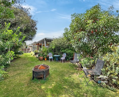Nestled in lush greenery, this inviting outdoor space features seating areas and a fire pit for gatherings.