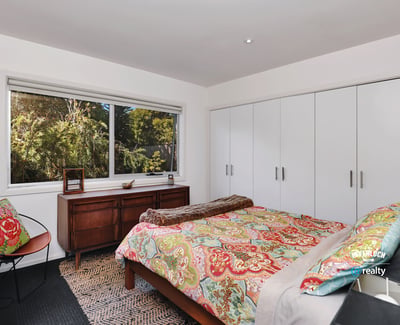 Bright bedroom featuring ample storage, a comfortable bed, and large windows showcasing natural surroundings.