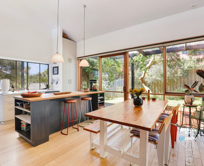 Bright and spacious kitchen with large windows, inviting natural light and views of the landscaped yard.