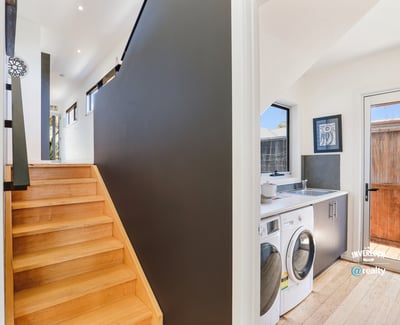 Modern entryway features a bright, airy stairway alongside a convenient laundry area and outdoor access.