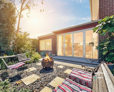 Enjoy outdoor gatherings in this inviting backyard, complete with a cozy fire pit and lush greenery.