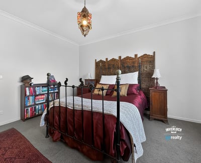 Cozy bedroom featuring a unique wooden headboard, warm lighting, and an inviting atmosphere for relaxation.