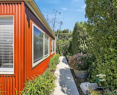 Lush landscaping surrounds this vibrant home, featuring a welcoming pathway and abundant greenery for outdoor enjoyment.